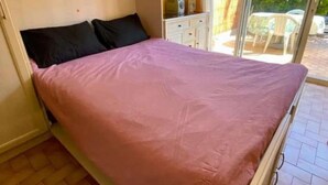 A single-bed room with a sliding door to a balcony, a small table, and a chair outside. - Cocon au Pradet - Beach, terrace & absolute calm (Le Pradet)