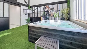 Ein moderner Innenbereich mit Whirlpool, einer Holzterrasse, einer Deckenleuchte und einem großen Fenster.