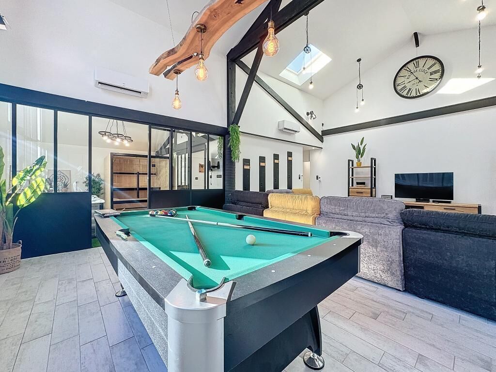 A modern living room with a pool table, a sofa, and a television.