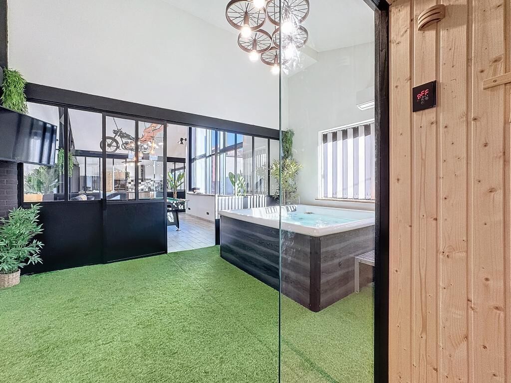 Un espace intérieur moderne doté d’une paroi en verre, d’un jacuzzi et d’un mur en bois sur lequel est fixé un panneau.