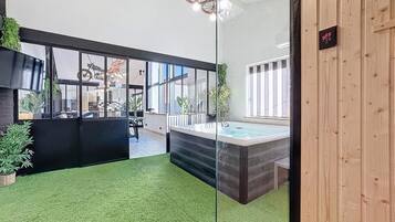 Un espace intérieur moderne doté d’une paroi en verre, d’un jacuzzi et d’un mur en bois sur lequel est fixé un panneau.
