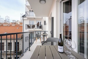 Un balcón con mesa, sillas, una botella de vino y copas de vino.