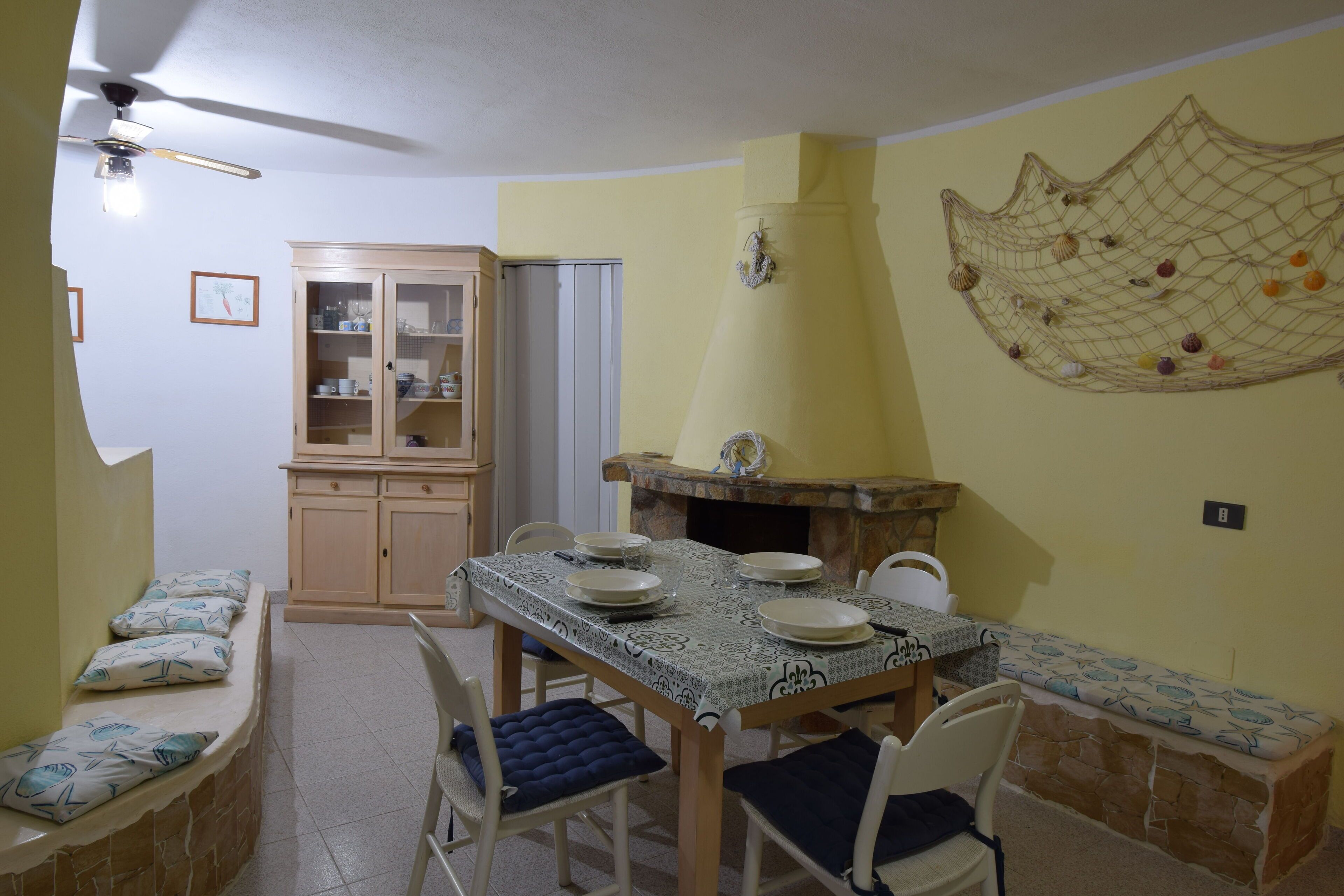Un coin repas avec une table dressée pour quatre personnes, un buffet en bois et un élément décoratif mural.