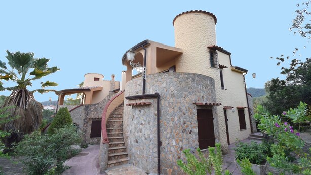 A building with a stone facade, a spiral staircase, and a small balcony. - Appartamento Tavernella In Budoni (Budoni)