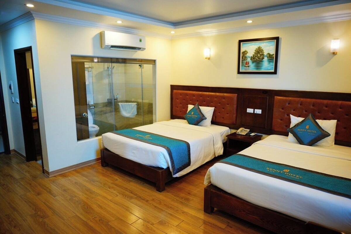 A hotel room with two beds, a shower area, and a painting on the wall.