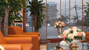 Et moderne interiør med orange sofaer, et glasbord og dekorative vaser med blomster.