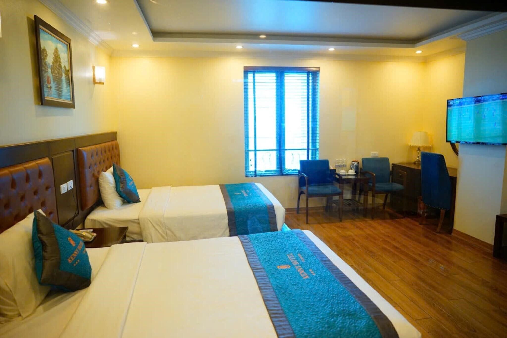A hotel room with two beds, a desk, a chair, a television, and a window with blinds.
