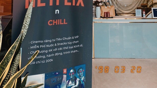 A hotel reception area with a large sign advertising a Netflix chill lounge, including amenities like cinema, snacks, and a 4K TV.
