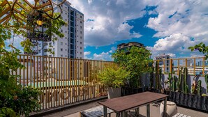 A rooftop terrace with a wooden pergola, a table, and benches.