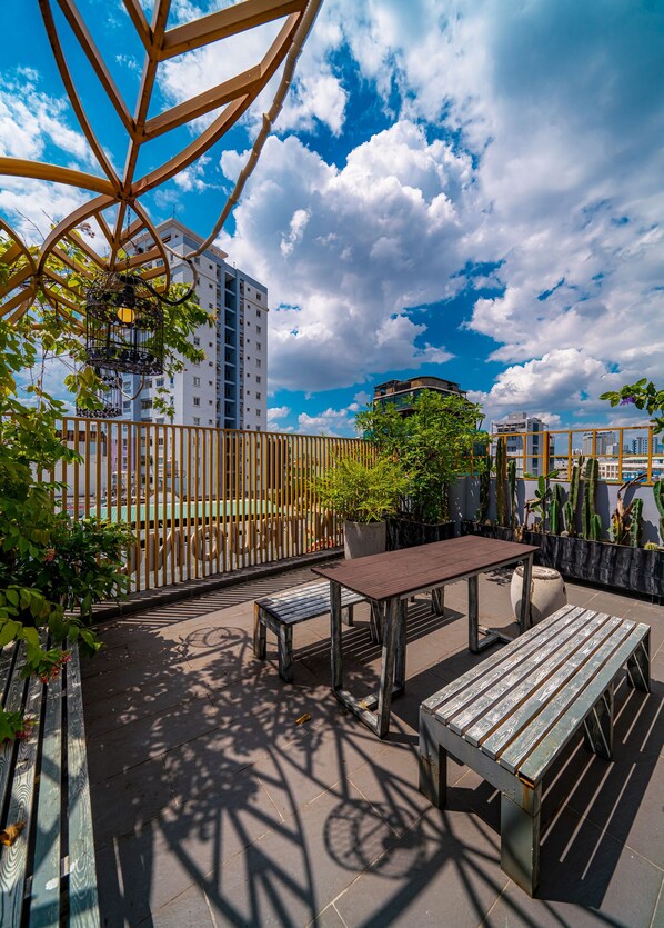 A rooftop terrace with a wooden pergola, a table, and benches.