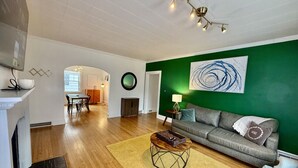 A spacious living room with a green accent wall, a grey sofa, and a wooden coffee table.