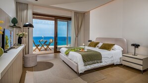 A modern bedroom with a bed, bedside table, and a view of the ocean.