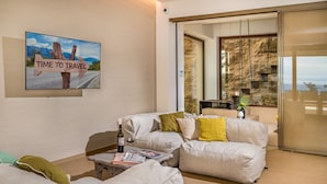 A living room with a sofa, coffee table, and a painting of a road sign.