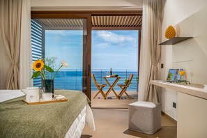A hotel room with a balcony, a bed with a tray of breakfast items, a small table with chairs, and a view of the sea. - Villa Mulberry 10 Emma Villas (Sciacca)