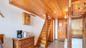 Un intérieur en bois comprenant un coin cuisine, un escalier en bois et un meuble avec un thermomètre.