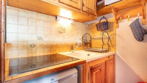 Une cuisine avec des meubles de rangement en bois, un évier et un égouttoir à vaisselle.