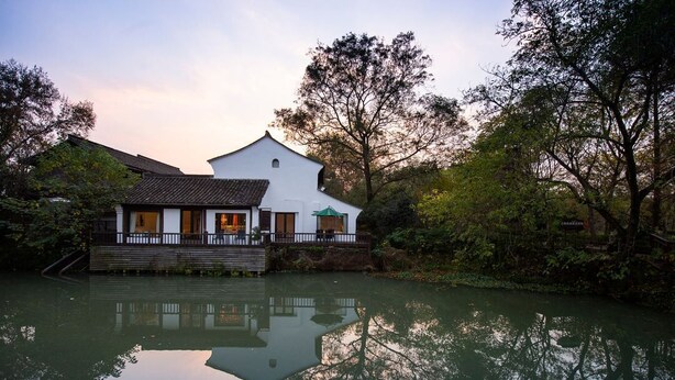 A traditional-style building with a reflection in the water, surrounded by trees. - Xishangyunjian (Hangzhou)
