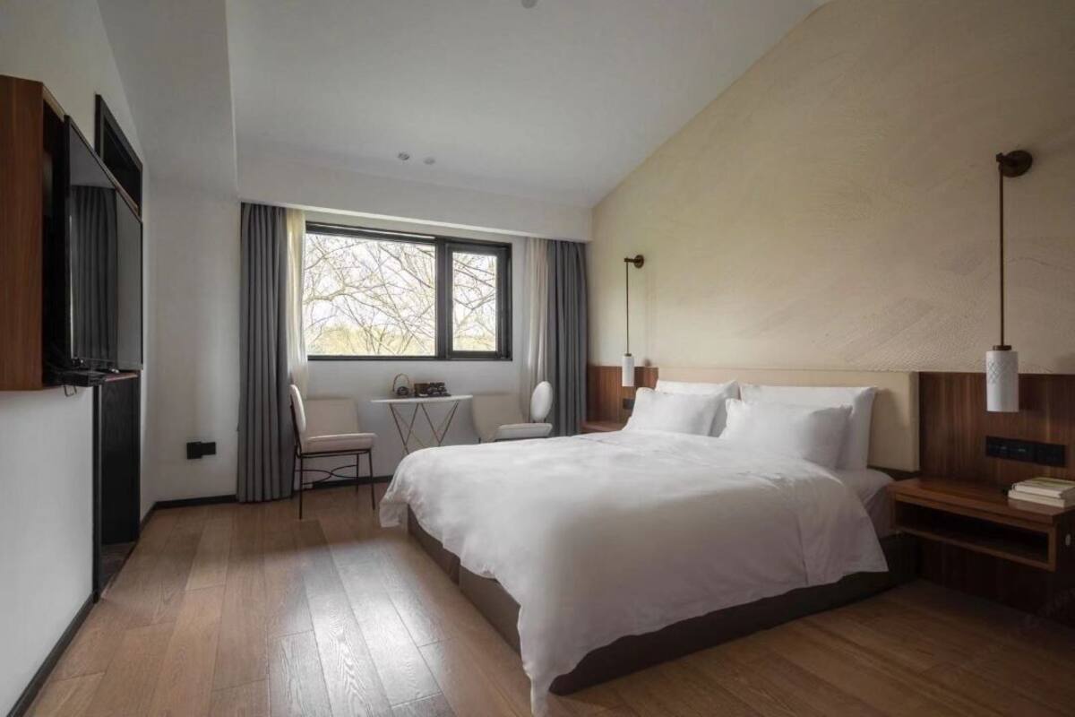 Ein modernes Hotelzimmer mit einem großen Bett, einem Schreibtisch und einem Fenster mit Vorhängen.