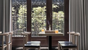 A dining area with a table and chairs, a vase with flowers, and a window with a view of greenery. - Xishangyunjian (Hangzhou)