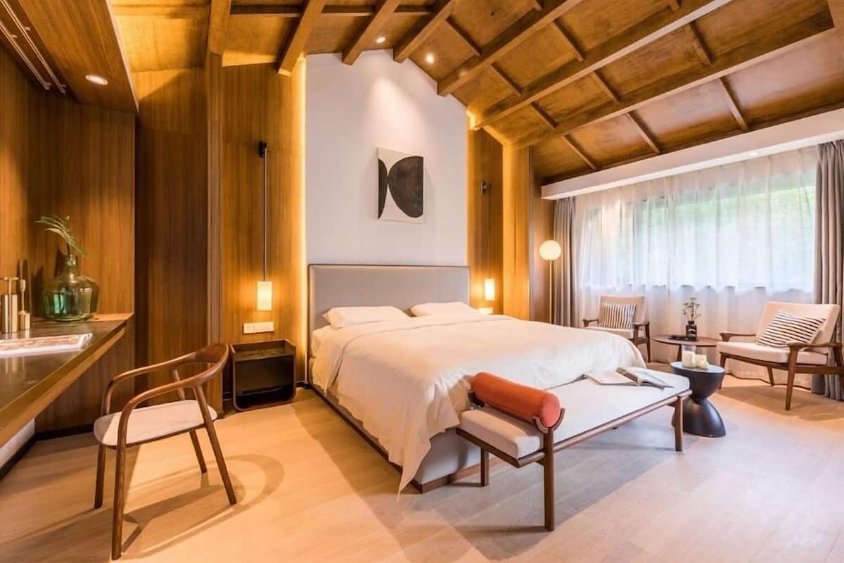 Ein modernes Schlafzimmer mit einem großen Bett, einem Schreibtisch, Stühlen und einem Fenster mit Vorhängen.