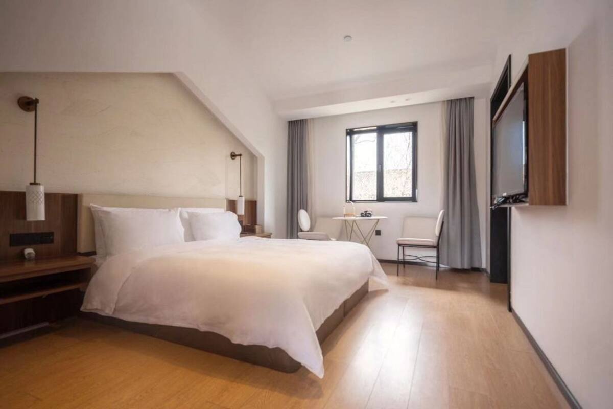 Ein modernes Hotelzimmer mit einem großen Bett, einem Schreibtisch, einem Sessel und einem Fernseher.