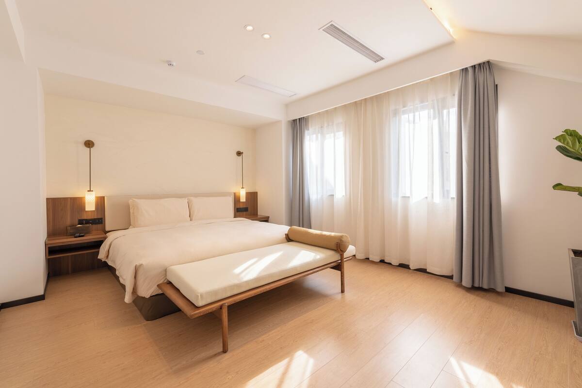 Ein modernes Hotelzimmer mit einem großen Bett, Nachttischen und einer Nachttischlampe.
