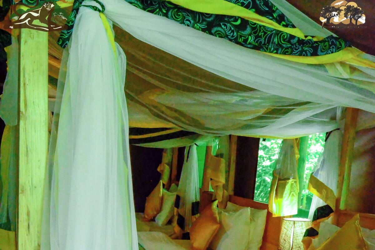 A bed with a canopy, pillows, and a floral bedspread.