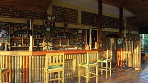 Een rustieke bar met houten stoelen en een achtergrond van een stenen muur.