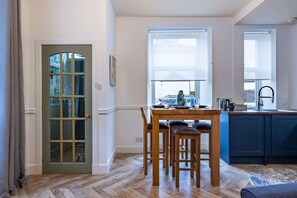Enjoy meals in the dining area with a wooden table and four chairs, adjacent to a fully equipped kitchen with a sink and stove.