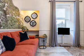 Relax in this stylish living room with a vibrant sofa, wall mural, and flat-screen TV.