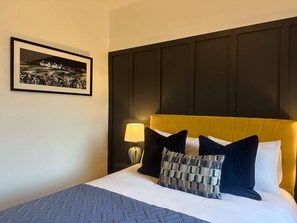 Relax in comfort with a large bed, framed artwork, and a bedside table.