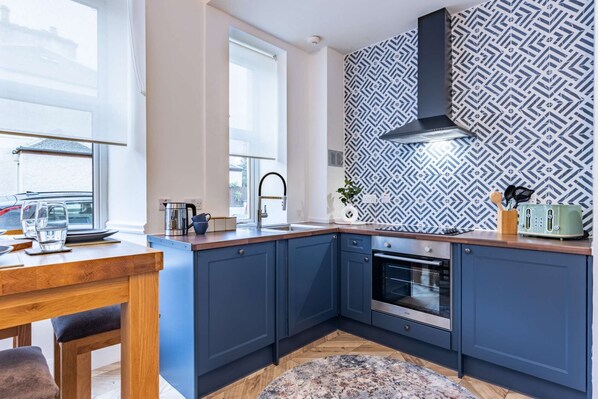 Enjoy meals in this kitchen with an oven, stainless steel range hood, and dining area with a view.