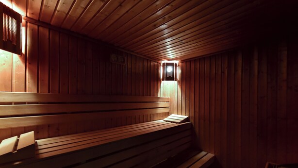 A wooden sauna with benches and a small window. - Chalet & Hotel IDA (Bansko)