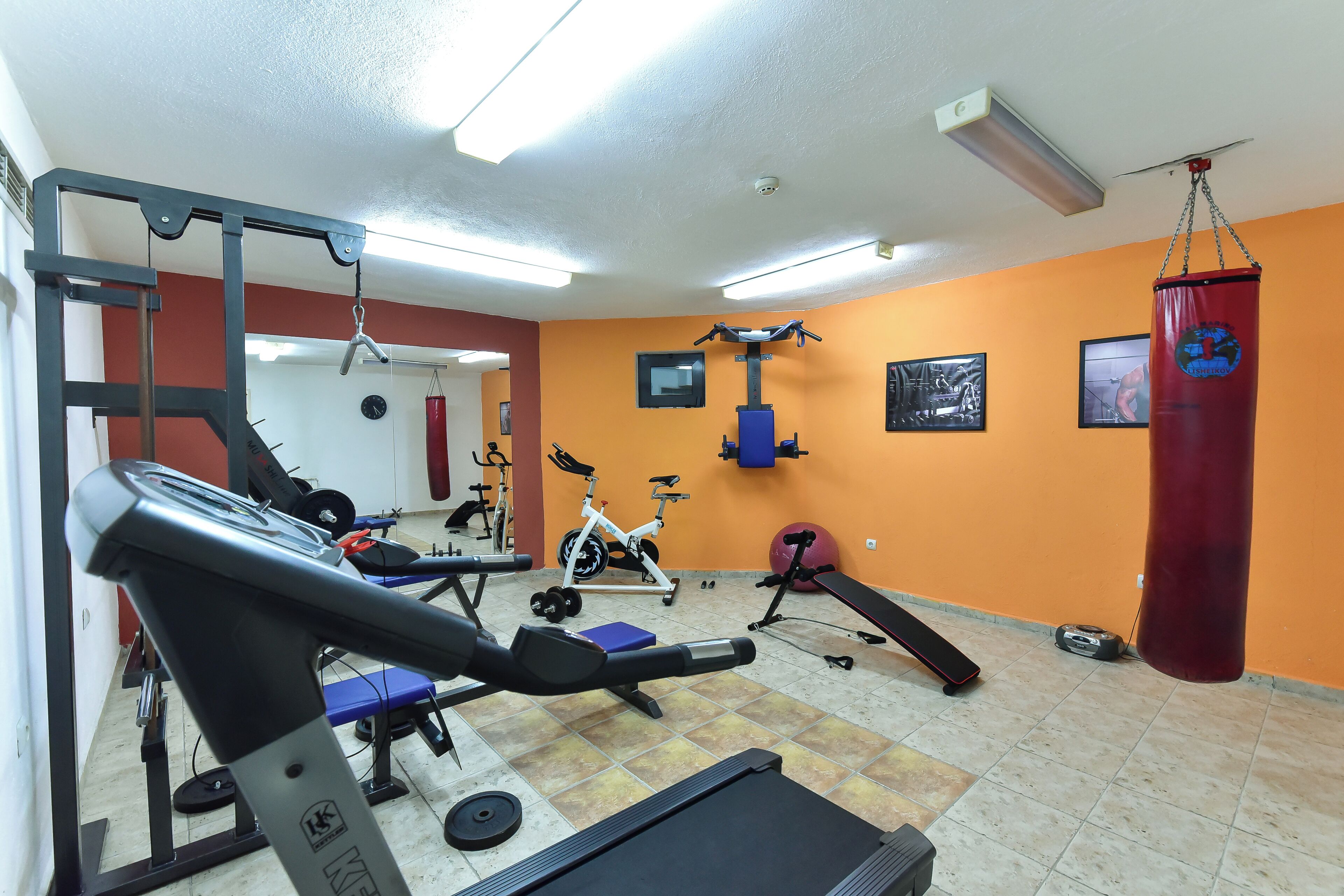 A gym with exercise equipment, a punching bag, and a mirror.