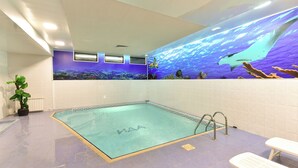 A swimming pool with a clear water surface, surrounded by tiled walls and a ceiling with recessed lighting. - Chalet & Hotel IDA (Bansko)