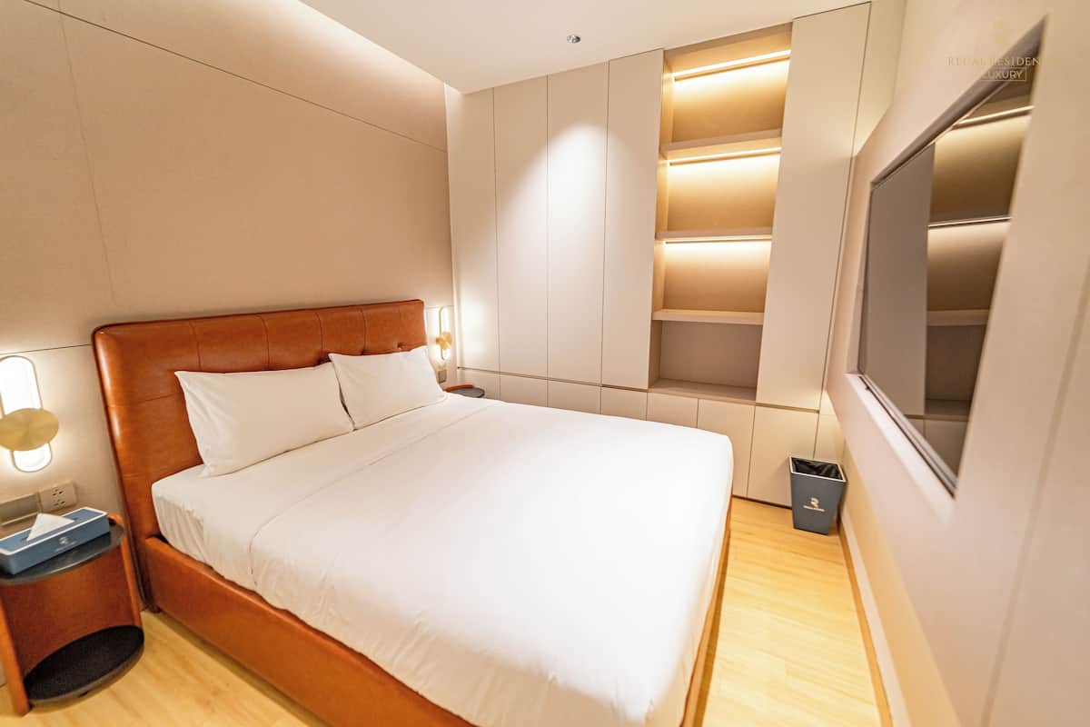 Ein modernes Schlafzimmer mit einem großen Bett, Einbauschränken und einem an der Wand montierten Fernseher.