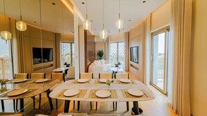 Un espace repas moderne avec une grande table ovale dressée pour un repas, entourée de sièges confortables.