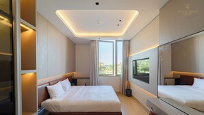 Une chambre d’hôtel moderne dotée d’un grand lit, d’un bureau, d’une télévision et offrant une vue sur la verdure environnante.