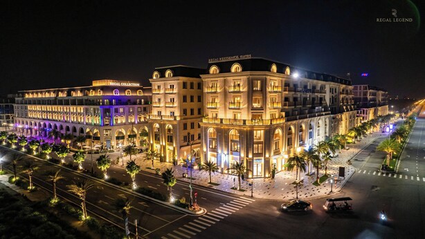 Un grand hôtel à plusieurs étages, doté d’arcades et de balcons, et situé sur une rue bien éclairée.