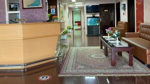 A hotel lobby with a reception desk, a chandelier, a map on the wall, a sofa, and a coffee table. - AZAIBA HOTEL APARTMENT (Muscat)