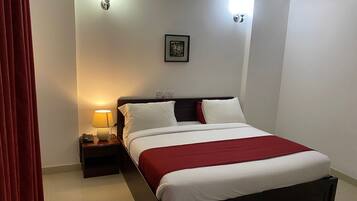 Una habitación de hotel con cama, mesita de noche, lámpara y un aplique de pared.