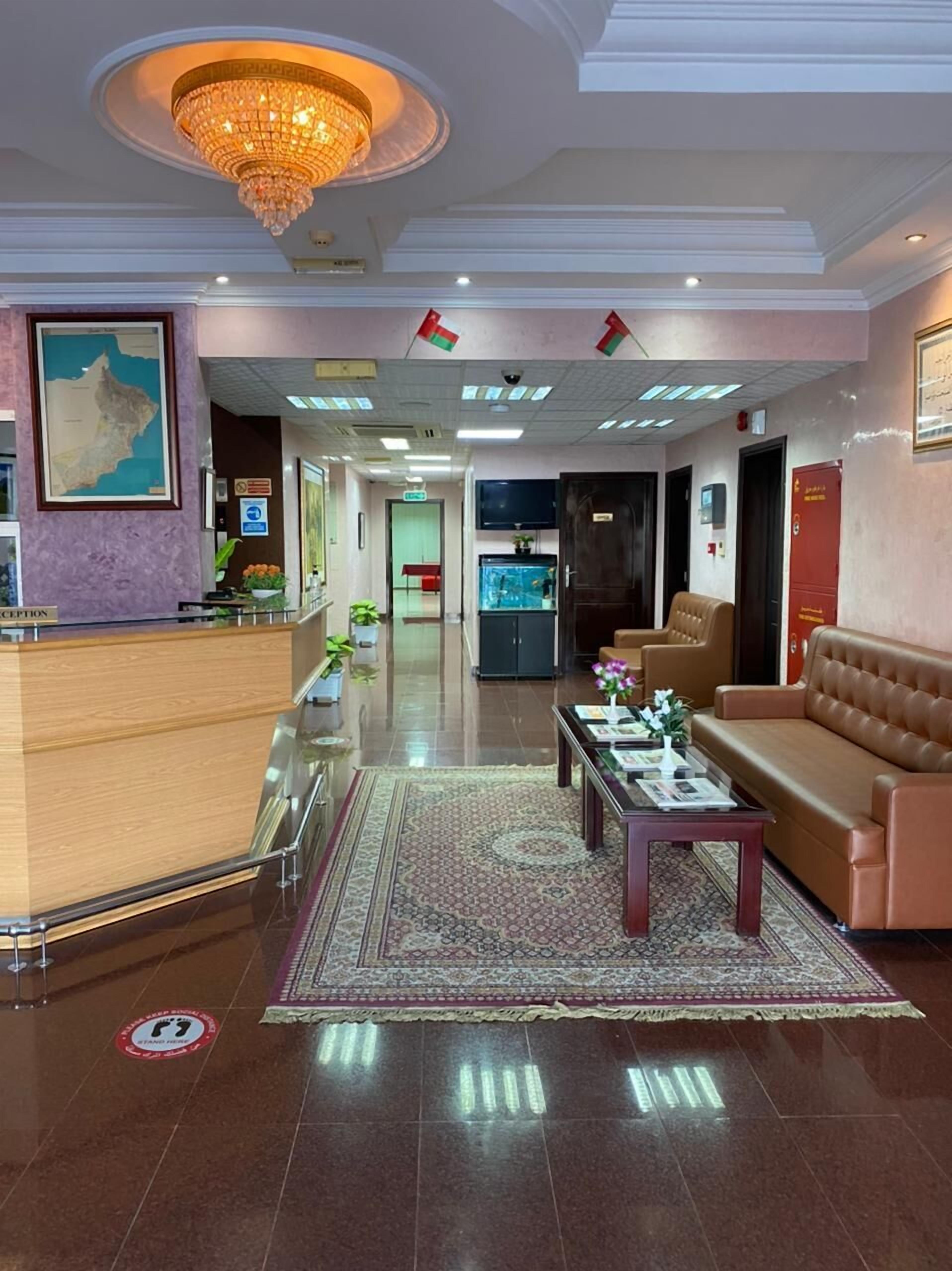 En hotellobby med en receptionsdisk, en soffa, ett soffbord, en kristallkrona och en karta på väggen.