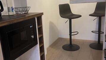 A kitchen with a built-in microwave, a wooden countertop, and two black bar stools.
