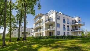 Een meerlaags woongebouw met balkons, een gazon en bomen.
