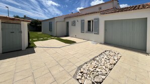 Un bâtiment moderne doté d’un toit en tuiles, d’une cour pavée et d’un petit jardin.