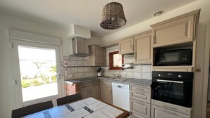 Une cuisine équipée d’une table à manger, d’un four encastré, d’un four à micro-ondes et d’un lave-vaisselle.