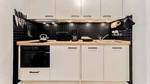 A modern kitchen with white cabinets, a black tiled backsplash, and a wooden countertop. - Jonathan - House Winora - Westerland (Westerland)