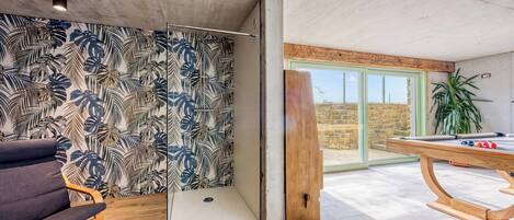Quarto com mesa de bilhar, uma cadeira e parede com padrão de folhagem tropical.