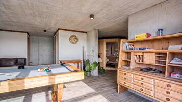 Una habitación con mesa de billar, armarios de madera y un reloj en la pared.