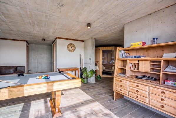 A room with a pool table, wooden cabinets, and a clock on the wall. - Villa Olivia with Sauna (Piran)
